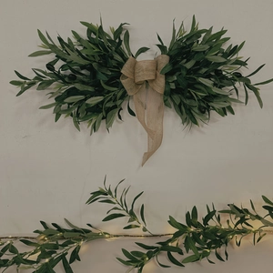 Detail of faux olive leaf wall hanging with burlap bow and dark green foliage