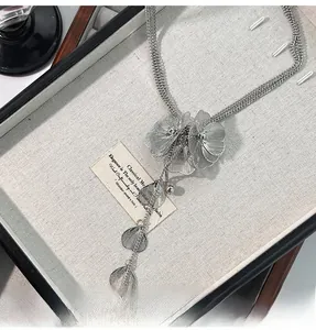Detailed view of silver mesh flower necklace with long tassels and multi-strand chains