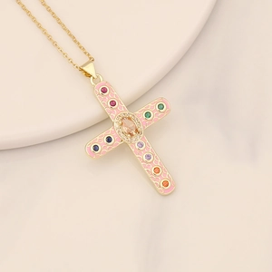 Detail of gold cross pendant with pink enamel and multicolor zircon stones on marble