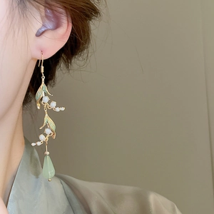 Detail of Lily of the Valley earrings with green teardrop pendants and gold leaf accents