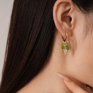 Detail of green leaf earrings with white zircon accents worn by a model in a close-up view