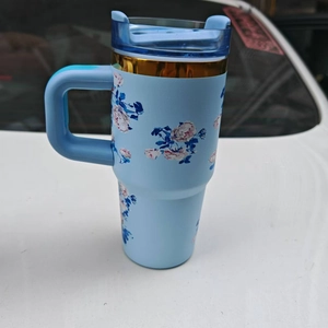 Close-up of light blue insulated tumbler with pink floral patterns and a gold trim