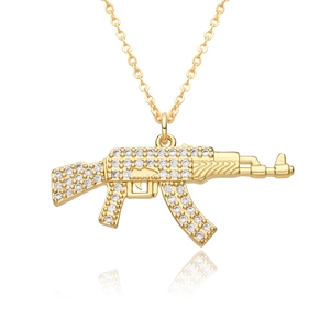 Macro shot of gold-plated AK-47 pendant with white zircons on a white background