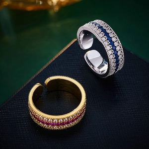 Macro shot of silver and gold compass rings with zircon pave on black textured surface