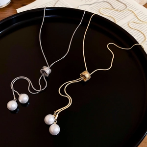 Détail de colliers à pompons réglables en or et argent avec perles sur un présentoir noir