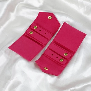Macro detail of rose red microfiber jewelry roll with gold snap button on white silk