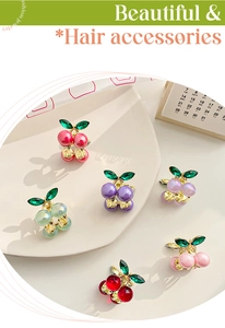 Detailed close-up of six colorful alloy cherry hair claws with rhinestones on a tray