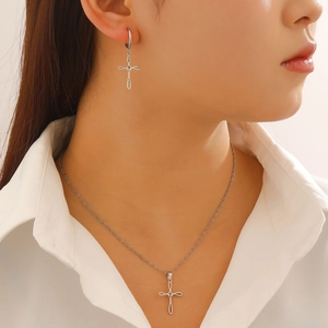 Macro view of silver cross pendant with knotted center detail on polished chain necklace
