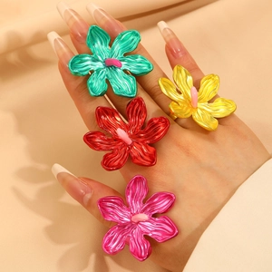 Detailed view of four colorful oversized vintage hollow flower rings on a model hand