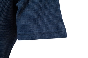 Detailed macro view of deep blue waffle knit texture and stitching on the shirt sleeve