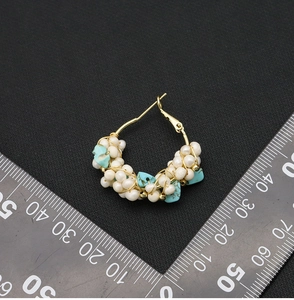 Macro detail of handmade pearl and turquoise hoop earrings shown with a size scale