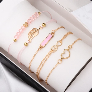 5-piece set of gold and pink heart bracelets with leaf and infinity charms on a white pillow