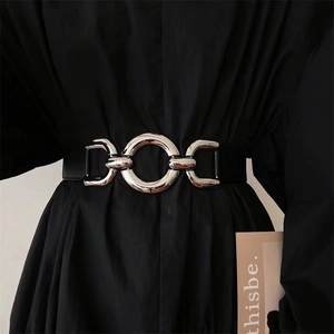 Elastic black waist belt featuring a bold golden metal interlocking ring buckle design