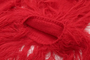 Gros plan d'un gilet rouge en maille avec une texture de franges en fausse fourrure douce