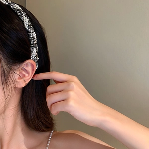 Elegant black and white tweed headband with pearl accents worn on dark wavy hair