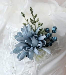 Détail d'une boutonnière de mariage bleu poudré avec roses en soie sur dentelle
