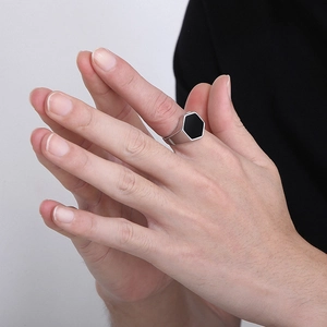 Macro detail of men's silver hexagonal ring with black inlay on finger