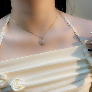 Detailed view of a golden snowflake pendant necklace with cubic zirconia on a model