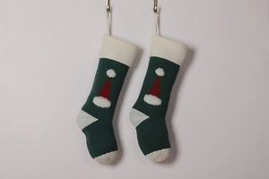 Detail of green and white knitted Christmas stockings with 3D red Santa hat pattern