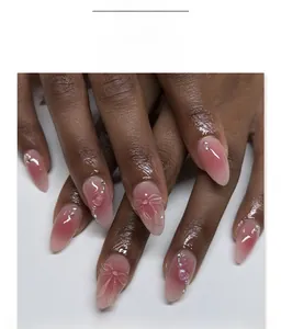 Detail of pink ombre almond press-on nails with 3D bows, pearls and rhinestones
