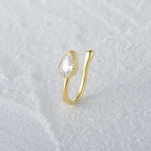 Detail of gold U-shaped nose cuff featuring a pear-cut crystal with milgrain edging