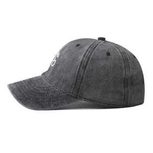 Close-up of white cherry embroidery and distressed texture on washed dark gray baseball cap