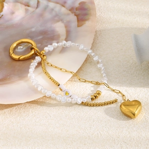 Détail du pendentif cœur plaqué or 18K et chaîne de perles sur fond de coquillage marin