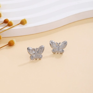Detailed view of silver butterfly earrings with textured metal wings on a warm backdrop