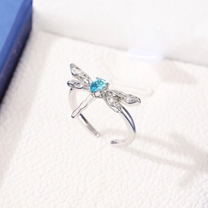 Macro shot of silver dragonfly ring with blue teardrop gemstone on leather jewelry box