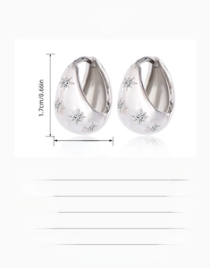 Detail view of silver teardrop hoop earrings with star patterns and zircon inlays