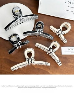 Detailed close-up of bow-shaped hair claws with Grace lettering on a wooden desk
