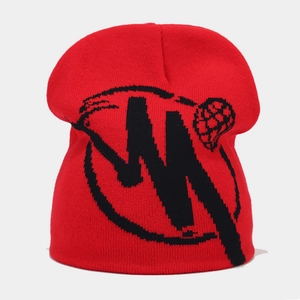 Detailed view of red knitted beanie featuring black abstract geometric jacquard patterns