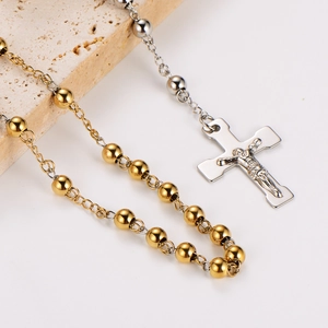 Two-tone stainless steel Y-necklace with cross pendant on textured stone background