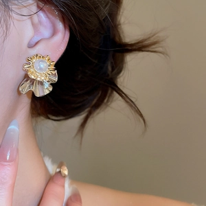 Close-up of elegant floral pearl earring in gold and silver finish on a model's ear