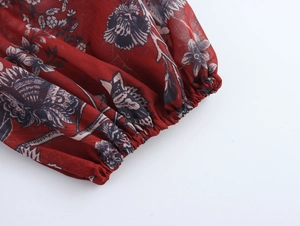 Close-up of floral print chiffon blouse showing elasticated cuff detail on red fabric