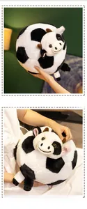 Close-up of a soft round plush cow doll being held to show its smooth velvet texture