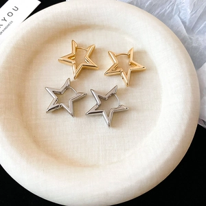 Close-up of gold and silver hollow star hoop earrings on a ceramic jewelry tray