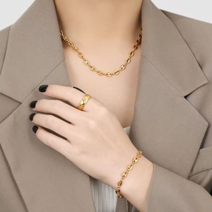 Close-up of luxury gold necklace, quilted ring and chain bracelet set on a model