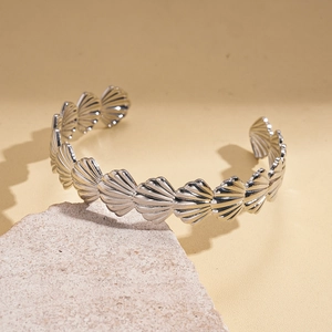 Detailed view of silver shell link bracelet on a textured stone over a warm background