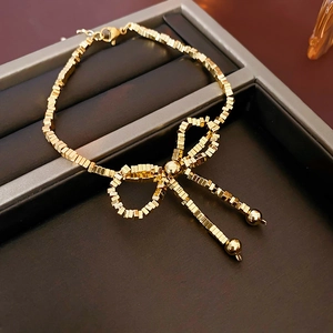 Detailed view of a gold bow bracelet with small cube beads and a secure lobster clasp