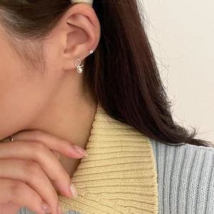 Close-up of minimalist sterling silver pearl hoop earrings worn by a model in soft light