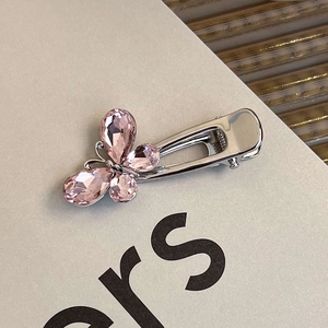 Macro detail of pink crystal butterfly hair clip with polished silver metal alligator base