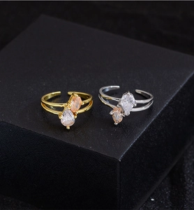 Close-up of gold and silver interlaced rings with teardrop cubic zirconia on dark display