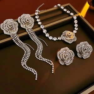 Détails de boucles d'oreilles fleurs à franges argentées et collier assorti en strass