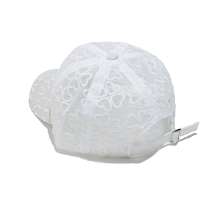 Dettaglio cappellino in pizzo bianco con motivi floreali e fibbia regolabile in metallo