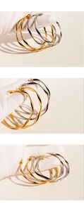 Macro detail of large gold and silver hoop earrings with twisted spiral metal texture