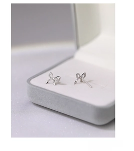 Macro shot of S999 sterling silver bow earrings displayed in a grey velvet jewelry box