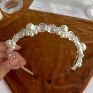 Close-up of a delicate pearl headband with transparent beads on a metal wire frame