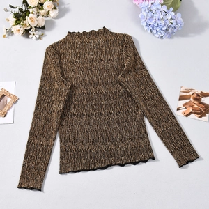 Détail d'un haut en maille marron doré avec texture côtelée et bords ondulés délicats