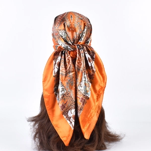 Detail of orange paisley silk square scarf worn as a stylish headband on a woman